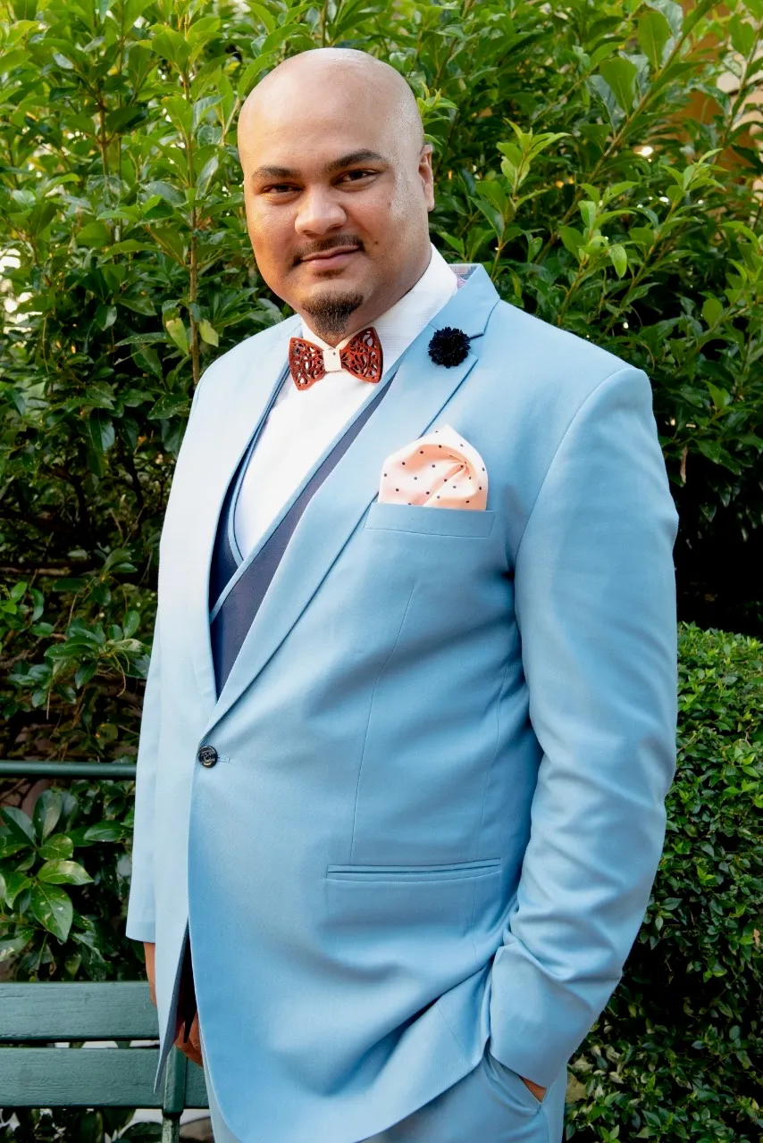 Rooshdean Solomons wearing a light blue suit outdoors.